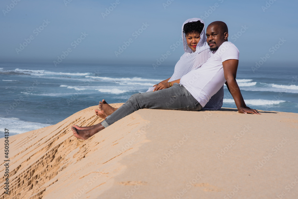Couple seen relaxing on sand dune 