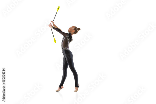 One Caucasian girl, rhythmic gymnastics artist practicing with baton isolated on white studio background. Concept of sport, action, aspiration, education, active lifestyle photo
