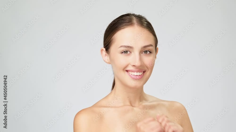 Beautiful Young Woman with Clean Fresh Skin standing over light grey background Beautiful Young Woman with Clean Fresh Skin standing over light grey background