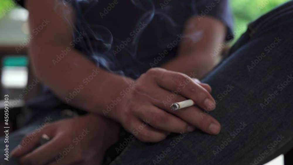 Closeup man cigarette burning smoke in hand. Tobacco smoke spreads carcinogens and the COVID-19 virus to people around. Smoking is health-destroying substance abuse. Closeup man cigarette burning smoke in hand. Tobacco smoke spreads carcinogens and the COVID-19 virus to people around. Smoking is health-destroying substance abuse.