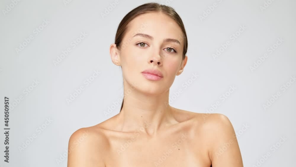Beautiful Young Woman with Clean Fresh Skin standing over light grey background Beautiful Young Woman with Clean Fresh Skin standing over light grey background
