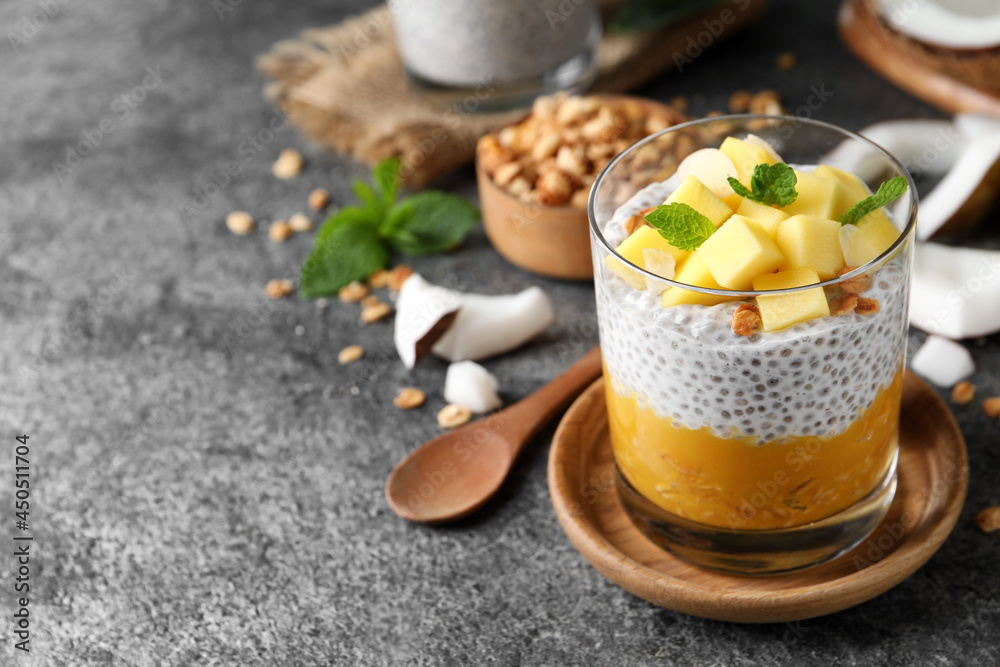 Delicious chia pudding with mango, mint and granola on grey table, space for text Delicious chia pudding with mango, mint and granola on grey table, space for text