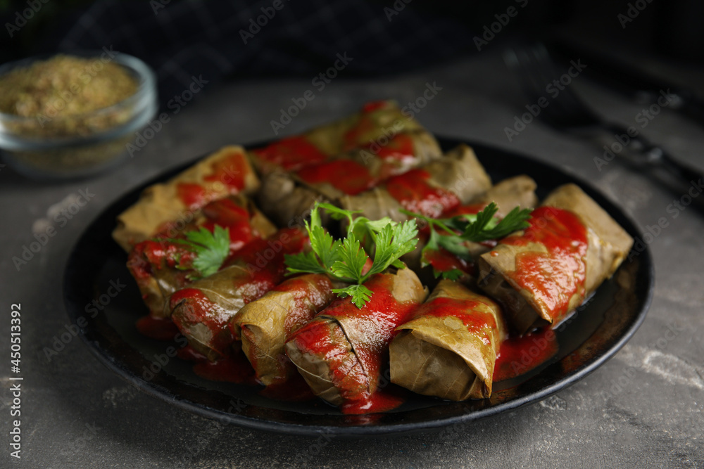 Delicious stuffed grape leaves with tomato sauce on grey table Delicious stuffed grape leaves with tomato sauce on grey table