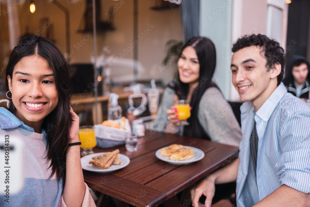 Group of friends taking a selfie, sitting outdoors in a bar.