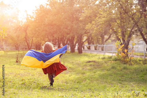 Girl with flag of Ukraine runs across the field close-up and copy space...