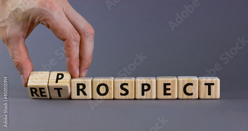 Prospect or retrospect symbol. Businessman turns wooden cubes and changes the word 'retrospect' to 'prospect'. Beautiful grey background. Business and prospect or retrospect concept. Copy space.