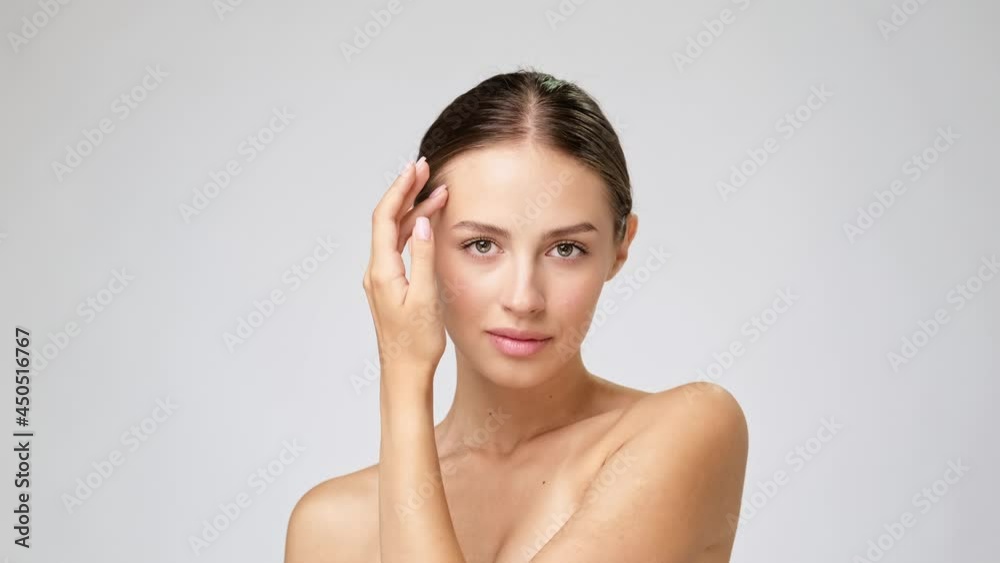 Beautiful Young Woman with Clean Fresh Skin standing over light grey background Beautiful Young Woman with Clean Fresh Skin standing over light grey background