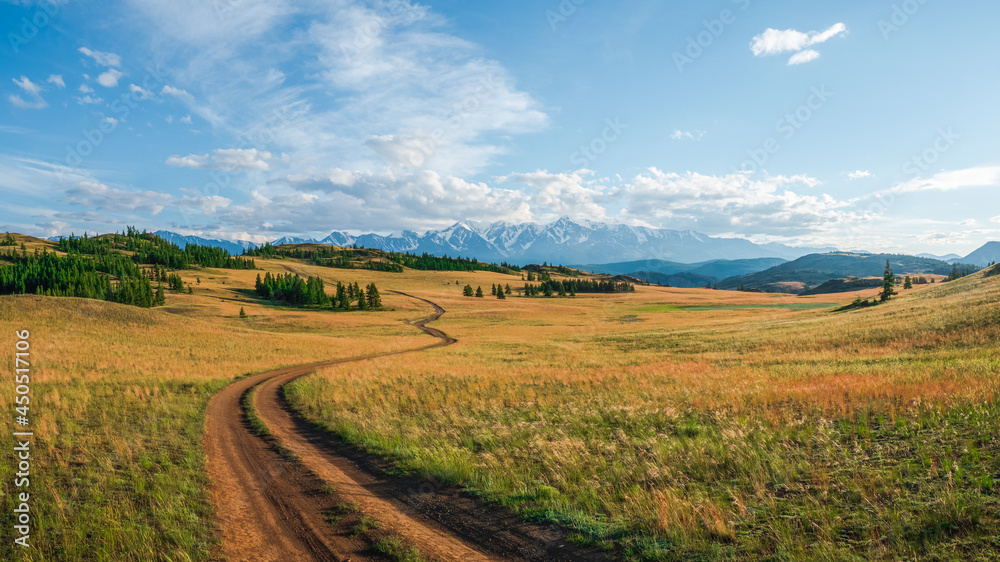 Autumn way up mountainside. Bright panoramic minimalist alpine landscape with stony footpath among grasses in highlands. Autumn way up mountainside. Bright panoramic minimalist alpine landscape with stony footpath among grasses in highlands.