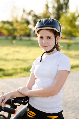11 year old girl in a helmet rides a bicycle. Girl with a bike in the park. Portrait of a child in a bicycle helmet © Анастасія Шатирова