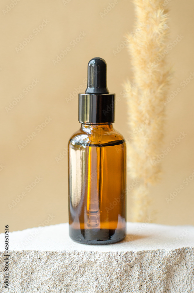 Brown bottle with a pipette on a beige background. Essential oil or serum and dry pompous herb on beige background Brown bottle with a pipette on a beige background. Essential oil or serum and dry pompous herb on beige background