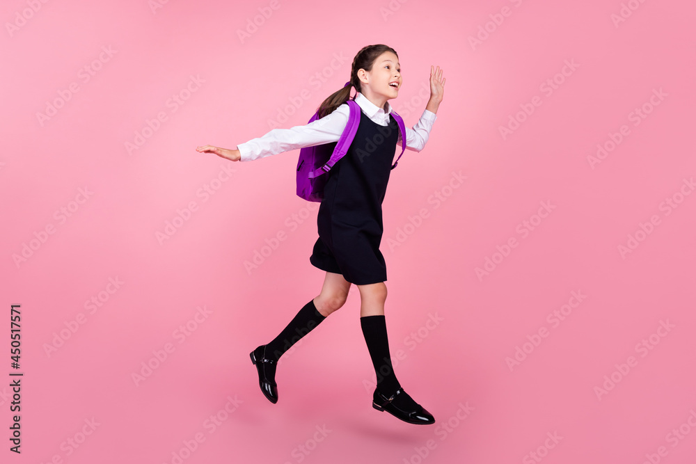 Full length body size photo schoolgirl jumping running on lesson waving hand isolated pastel pink color background Full length body size photo schoolgirl jumping running on lesson waving hand isolated pastel pink color background