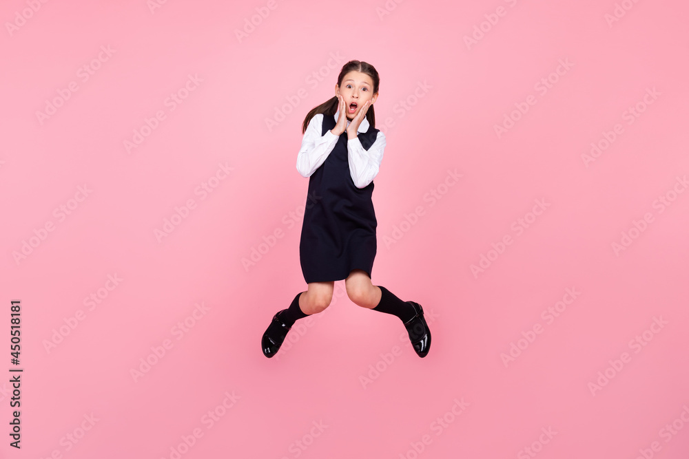 Full length body size photo schoolgirl jumping up touching cheek amazed isolated pastel pink color background Full length body size photo schoolgirl jumping up touching cheek amazed isolated pastel pink color background