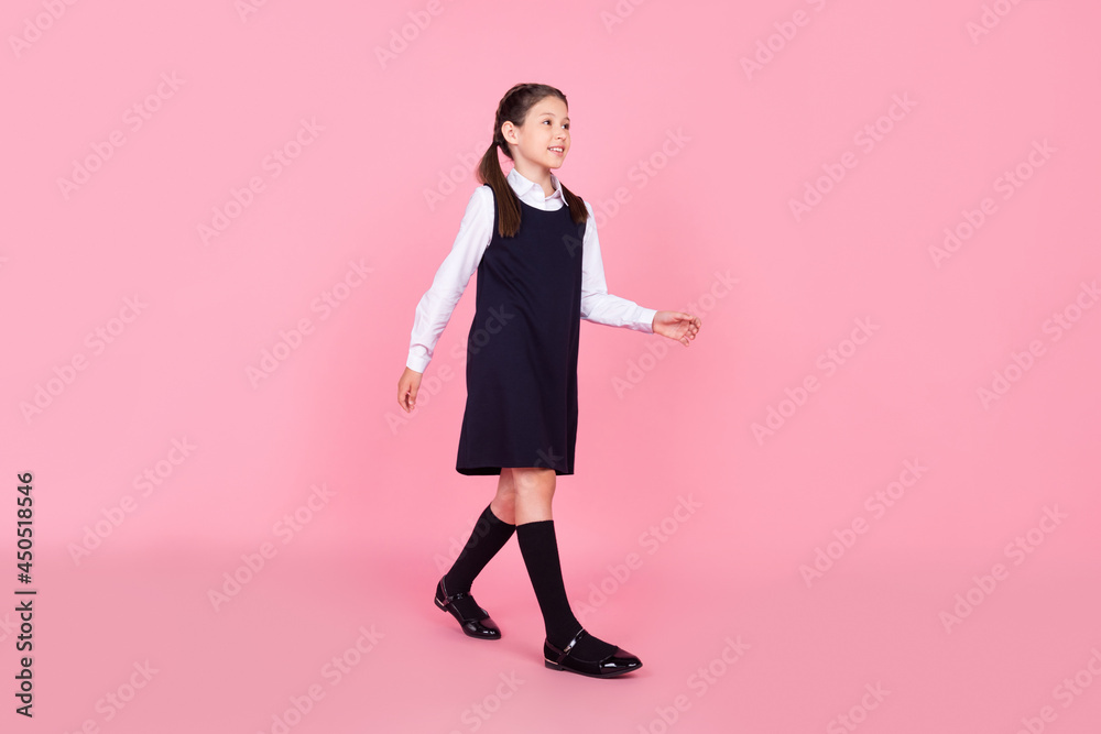 Full length body size photo schoolgirl in uniform walking on lesson looking copyspace isolated pastel pink color background Full length body size photo schoolgirl in uniform walking on lesson looking copyspace isolated pastel pink color background