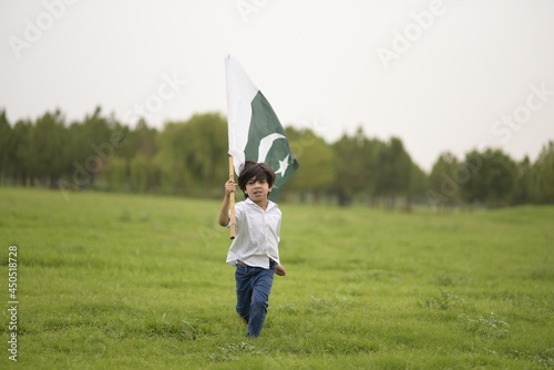 cheerful active little boy celebrating 14th of August, Pakistan Independence day with waving Pakistani flag. F-9 Park Islamabad, Pakistan.
