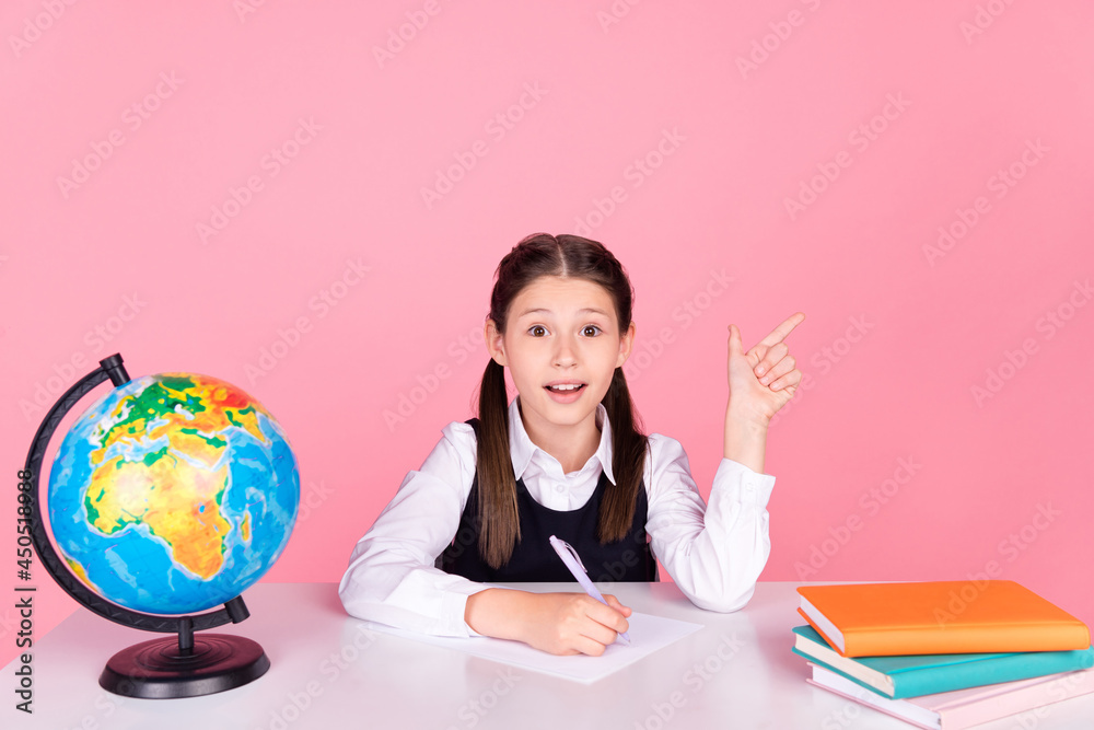Photo portrait little girl with tails sitting at desk writing exam showing copyspace isolated pastel pink color background Photo portrait little girl with tails sitting at desk writing exam showing copyspace isolated pastel pink color background