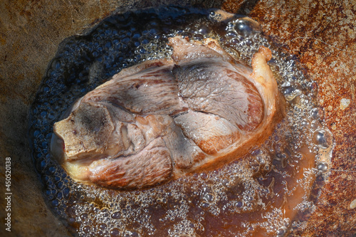 A piece of meat is fried in boiling oil.