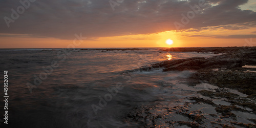 Long exposure sunset with rolling waves, fluffy, rocks and clouds 2