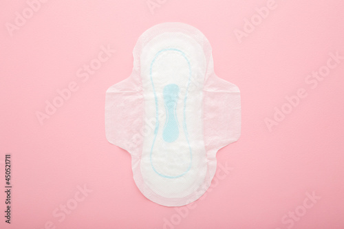 New opened white sanitary towel on light pink table background. Pastel color. Closeup. Female hygiene. Top down view.
