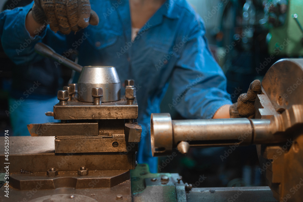 hands of the master rotate the handle on the lathe.