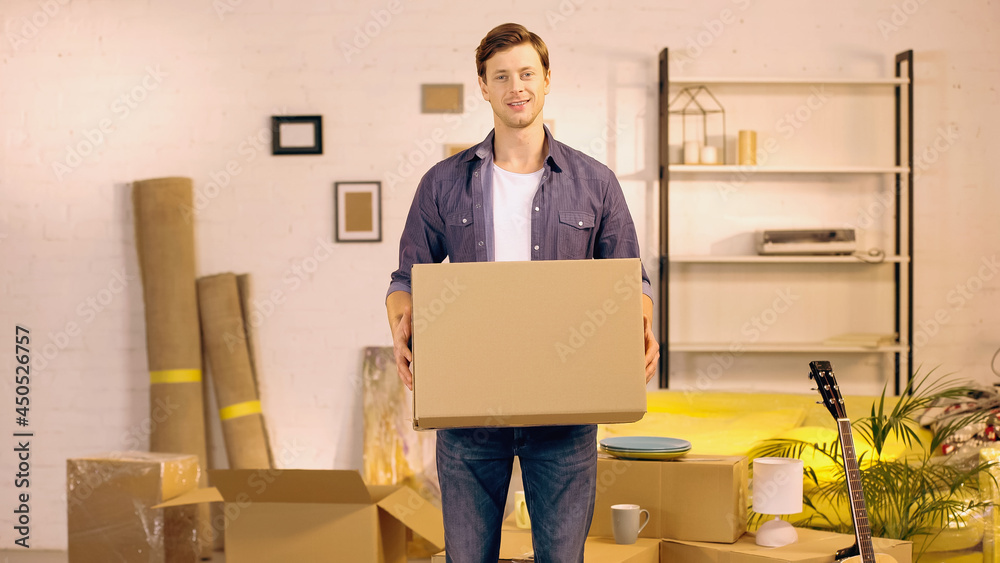 happy young man holding cardboard box in new home happy young man holding cardboard box in new home