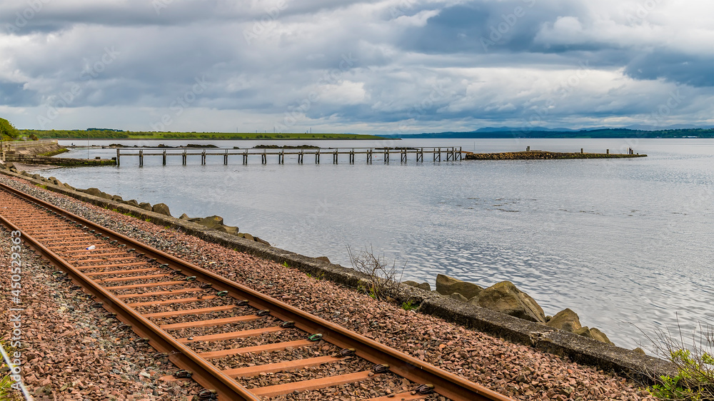 A view over the coastal railawy towards the pier at Culross, Scotland on a summers day