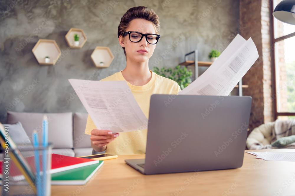 Photo of sweet serious young lady wear yellow t-shirt sitting table working with papers modern gadget indoors room home Photo of sweet serious young lady wear yellow t-shirt sitting table working with papers modern gadget indoors room home