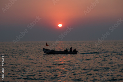 The perfect sunset at the background and the people sailing in the boat in the foreground. 