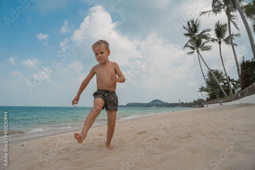 Boy playing barefoot soccer on the beach with a black and white ball on an island by the sea