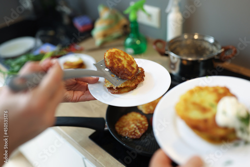 Chef preparing fried potato pancakes in frying pan closeup