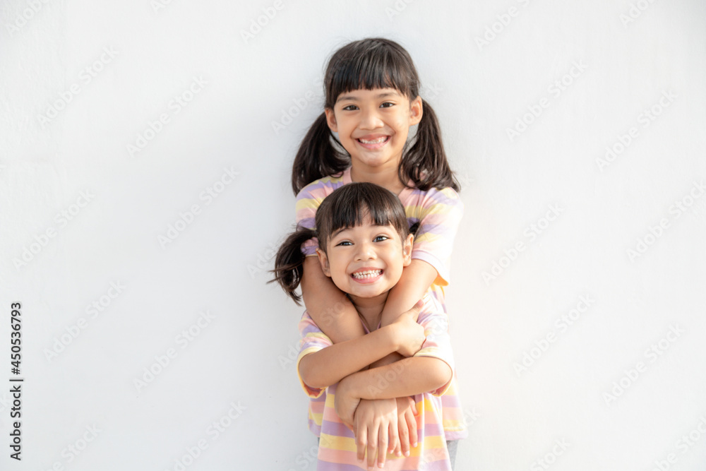 Cute happy Asian siblings hugging cuddling feeling love and connection, smiling kid girl sister embracing little girl sister on white background, 2 children good relationships Cute happy Asian siblings hugging cuddling feeling love and connection, smiling kid girl sister embracing little girl sister on white background, 2 children good relationships