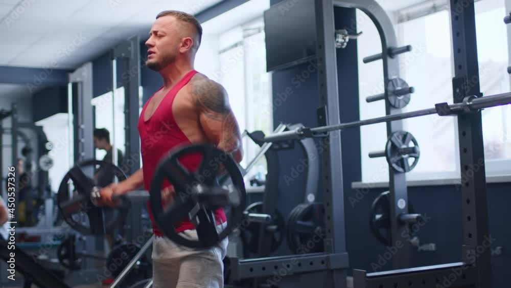 Male athlete doing barbell curl exercise in a gym Male athlete doing barbell curl exercise in a gym
