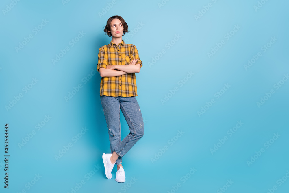 Photo of pensive lady crossed arms look empty space wear plaid shirt jeans shoes isolated blue color background Photo of pensive lady crossed arms look empty space wear plaid shirt jeans shoes isolated blue color background