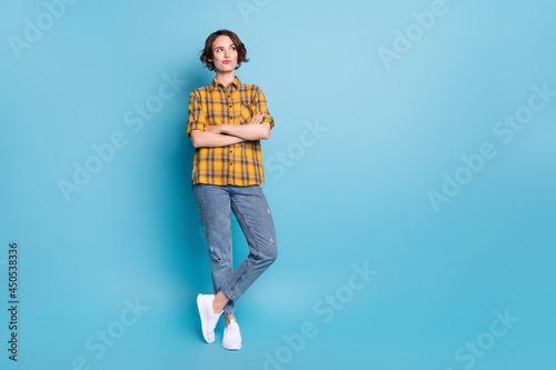 Photo of pensive lady crossed arms look empty space wear plaid shirt jeans shoes isolated blue color background