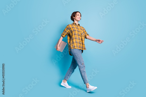 Profile photo of lady stroll hold netbook empty space wear checkered shirt jeans shoes isolated blue color background