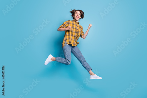 Photo of champion crazy lady jump scream raise fists wear plaid shirt jeans shoes isolated blue color background