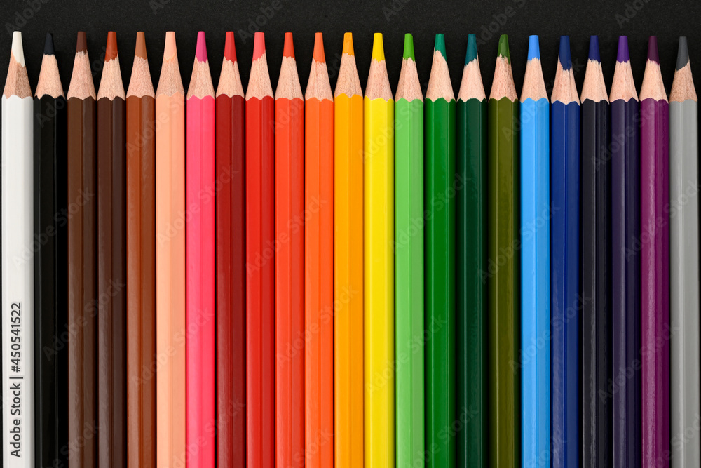 Colored pencils on a black cardboard background. Top view. Education concept. High-quality photo Colored pencils on a black cardboard background. Top view. Education concept. High-quality photo