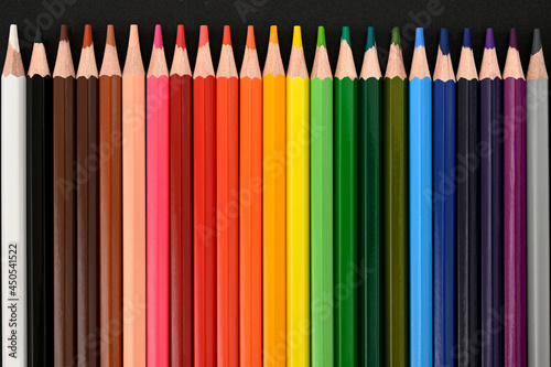 Colored pencils on a black cardboard background. Top view. Education concept. High-quality photo 