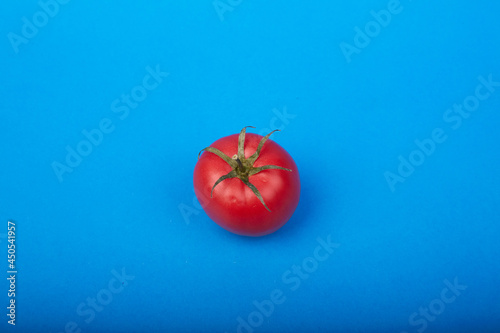 one ripe tomato on a blue background