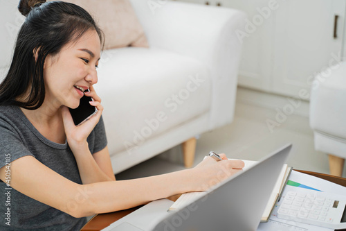 happy Young asian woman  working with laptop in bed at home in the morning.