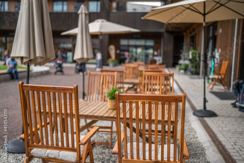 Fototapeta Naklejka Na Ścianę i Meble -  Wooden chairs with a green flowers in the middle of the table of an outdoor restarurant