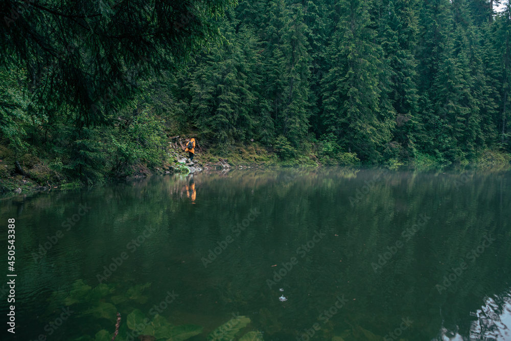 Fototapeta premium woman hiker in yellow raincoat at lake beach