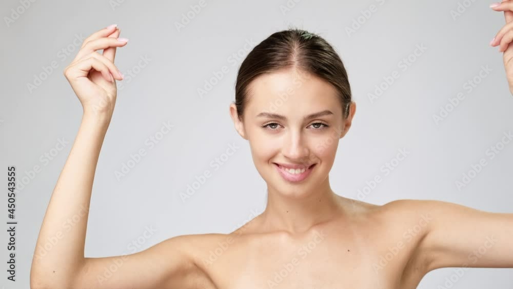 Beautiful Young Woman with Clean Fresh Skin standing over light grey background Beautiful Young Woman with Clean Fresh Skin standing over light grey background
