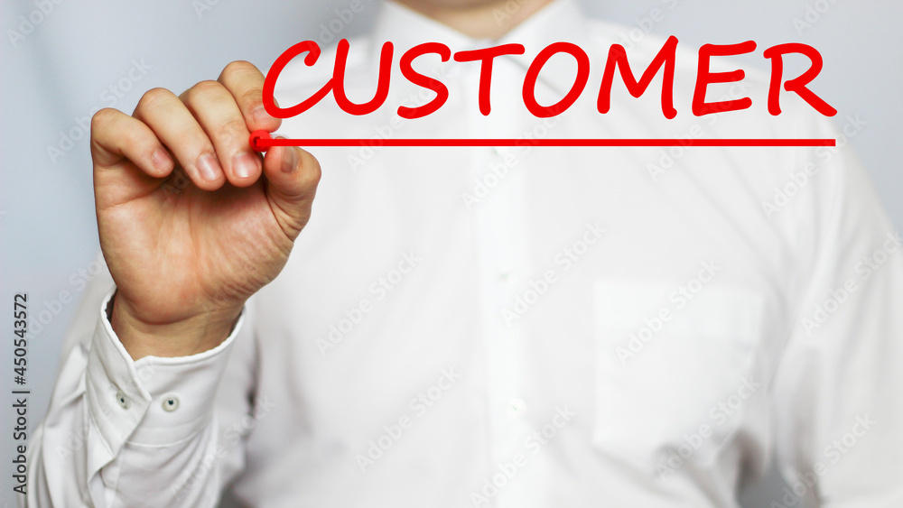 A businessman in a white shirt writes a text CUSTOMER on a white background with a red marker . business concept A businessman in a white shirt writes a text CUSTOMER on a white background with a red marker . business concept