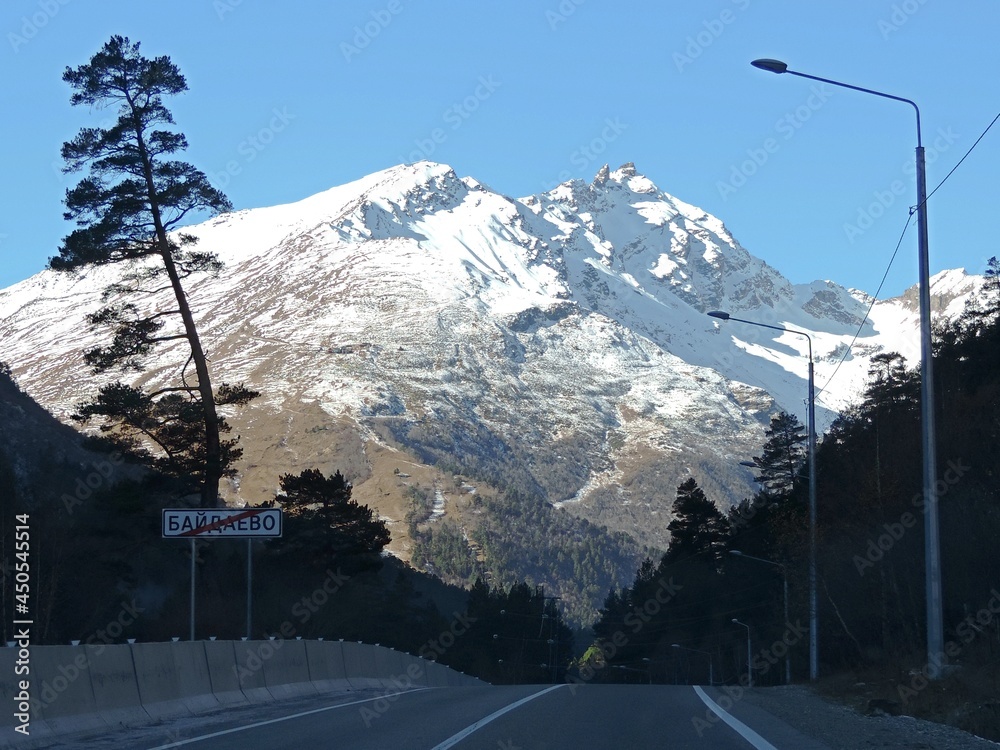 Fototapeta premium View on the road to the Mountains in summer with snow, blue sky on a clear day. 