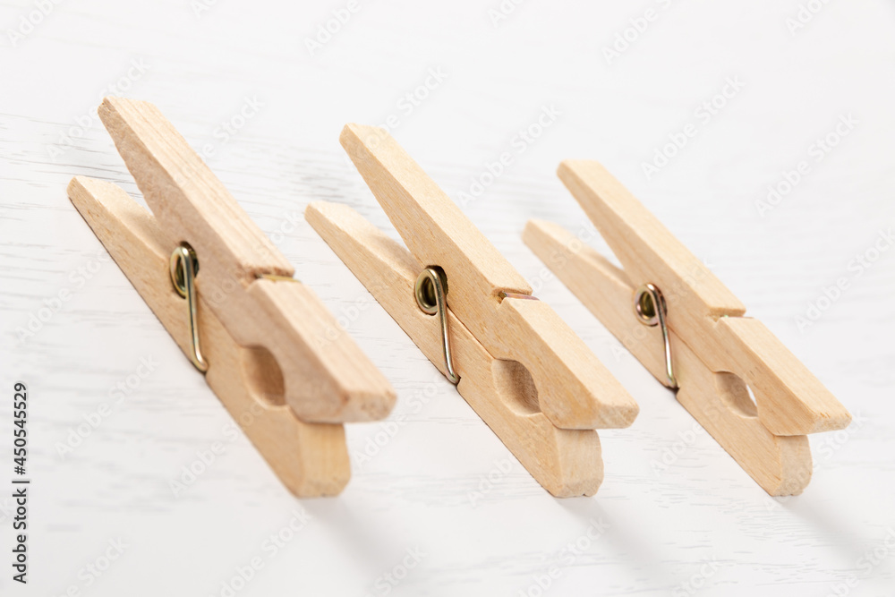 three wooden clothespins with a metal spring on the background of a white wooden table. close-up. selective focus three wooden clothespins with a metal spring on the background of a white wooden table. close-up. selective focus