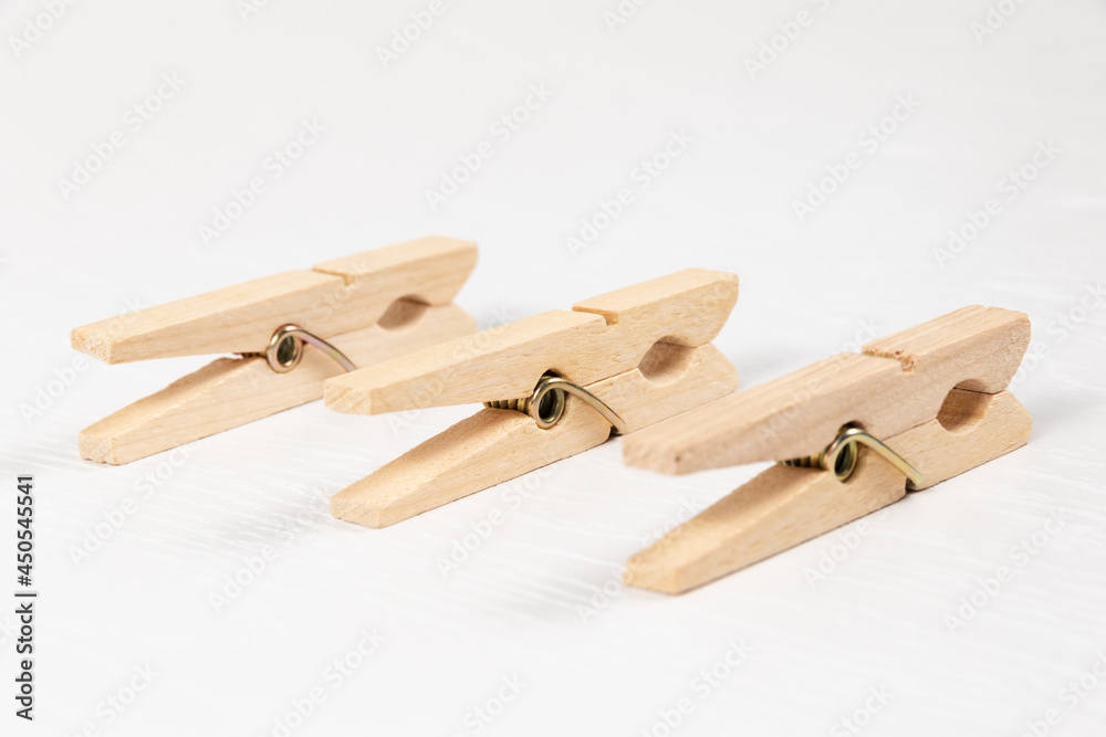 three wooden clothespins with a metal spring on the background of a white wooden table. close-up. selective focus three wooden clothespins with a metal spring on the background of a white wooden table. close-up. selective focus