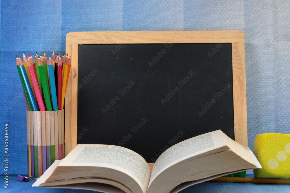 A black board with copy space and school supplies and a book. A black board with copy space and school supplies and a book.