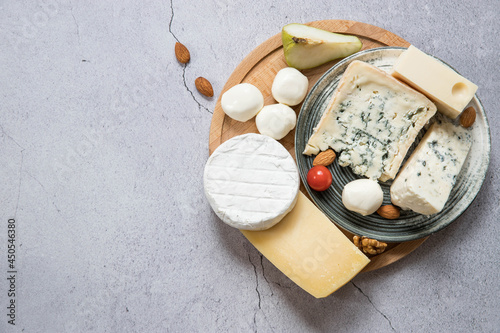 Cheese board on a gray background top view with a copy space .  Mixed cheese  .  Parmesan , camembert , brie , mozzarella  and masdam on a gray background top view .  Cheese store .  Cheese menu .  photo