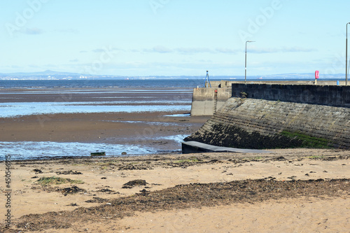 Photography View of River at Low Tide from Sandy Beach with Old Stone Harbour Wall