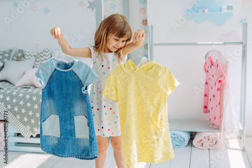 Canvas-taulu Beautiful little girl choosing a dress in the kids room